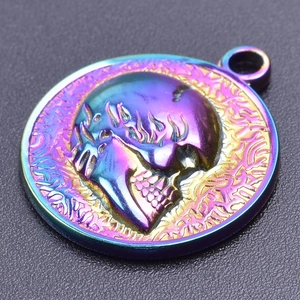 Macro shot of circular skull pendant with iridescent finish and flame-detailed relief