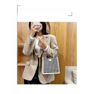 Close-up of black and white houndstooth canvas tote bag with woven handles and button