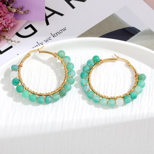 Detailed shot of handmade gold wire hoop earrings with green and white textured beads
