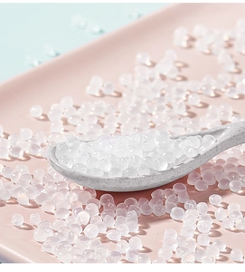 Close-up of clear spherical silicone beads on a pink tray with a grey spoon detail