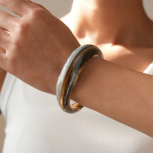 Detailed view of a thick tortoiseshell acrylic cuff bracelet with marble texture on wrist