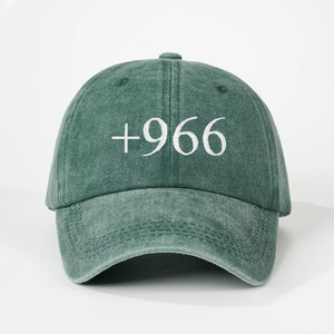 Detailed macro view of white +966 embroidery on dark green washed cotton baseball cap