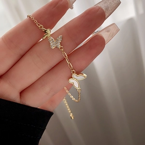Detail of gold butterfly bracelet with zircon inlay and mother of pearl on woman wrist