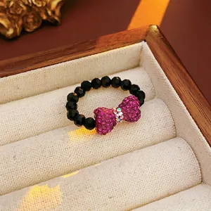 Beaded ring with a purple rhinestone bow accent displayed in a premium wooden jewelry box