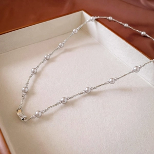 Detailed shot of silver-colored chain necklace with grey pearl beads in jewelry box