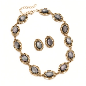 Vintage gold metal jewelry set with oval gray resin stones and embossed necklace and earrings