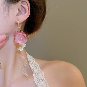 Detail of pink fabric flower earrings with golden wavy tassels and pearl bud accents
