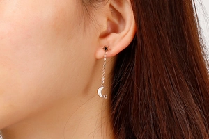 Detail shot of silver star and moon tassel earrings worn by a model in a close-up view