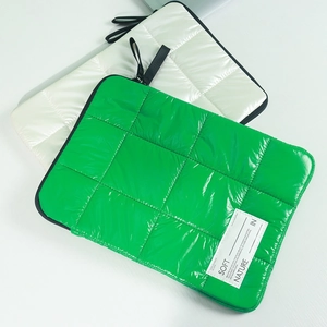Close-up of green and white quilted space cotton laptop sleeves with soft padded texture