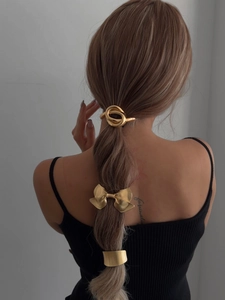 Detailed close-up of golden bow-knot and round alloy hair clips on a braided hairstyle