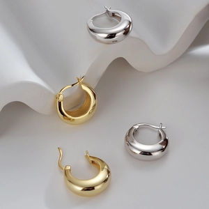 Polished chunky gold and silver teardrop hoop earrings on a white minimalist background