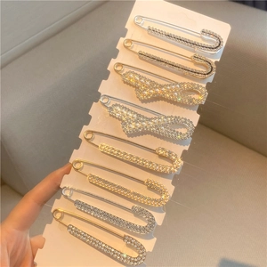 Close-up of 8 rhinestone and pearl decorative waist pins on a white display card