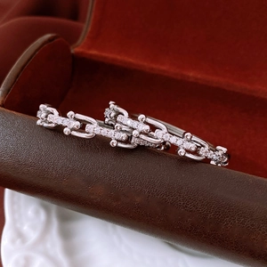 Macro shot of silver paved diamond U-shaped chain link earrings on a leather box