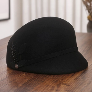 Close-up of elegant black wool equestrian hat featuring sequined leaf and metal emblem
