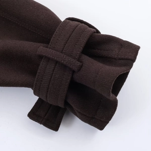 Gros plan des poignets du manteau marron foncé avec sangle décorative en laine