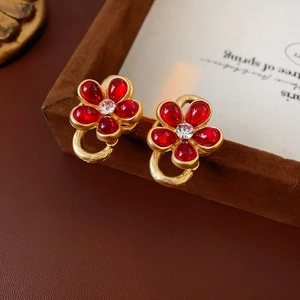 Detail of vintage gold flower earrings with red semi-precious petals and crystal centers