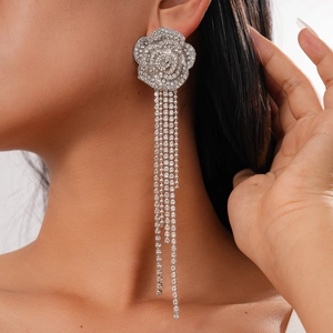 Close-up of sparkling rhinestone flower earrings with long tassel chains on a model