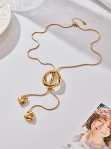 Detail of golden snake chain Y-necklace with irregular ring and dual heart pendants