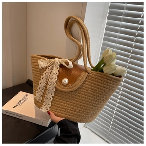 Detail of straw woven bag with brown leather flap, pearl clasp and beige lace ribbon
