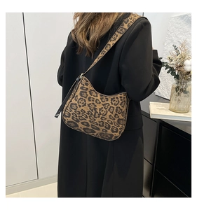 Detailed view of leopard print shoulder bag with wide strap on model in modern interior