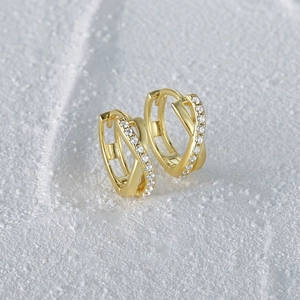 Macro shot of gold hoop earrings with criss-cross pattern and white zircon inlay
