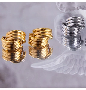 Dettaglio orecchini a nodo intrecciato color oro e argento con riflesso a specchio