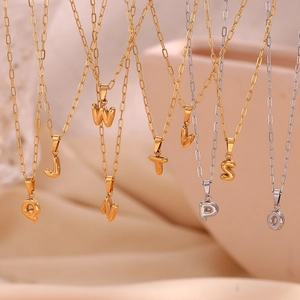 Macro detail of 3D gold and silver bubble letter pendants on paperclip chain necklaces
