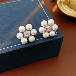 Detailed close-up of pearl flower earrings on a luxury navy jewelry box background