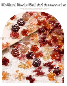 Macro detail of brown resin 3D camellia and butterfly nail charms in Maillard autumn tones