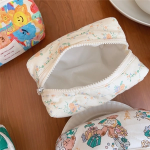 Quilted cotton cosmetic bags with bear and floral patterns on a warm wooden desk