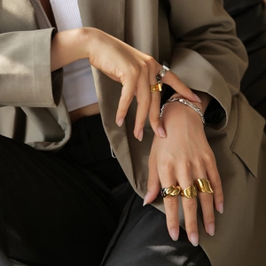 Detailed close-up of a stack of mixed gold and silver chunky irregular rings on a hand