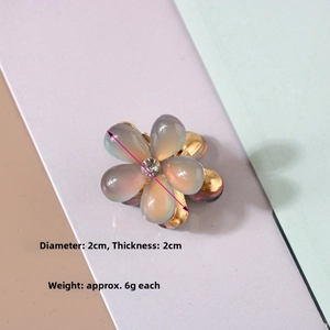 Detailed close-up of small resin flower hair claw with pearl and 2cm diameter scale