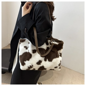 Detail view of large plush cow print tote bag with brown faux fur and leather strap