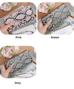 Three snakeskin pattern wallets in pink, green, and grey on a rustic wooden table