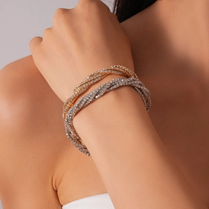 Detail of layered gold and silver bracelets with sparkling zircon stones on model's wrist