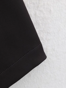 Detail of double-needle stitching and texture on black woven puff sleeve dress fabric