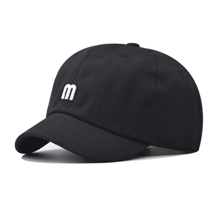 Close-up of white 3D letter 'm' embroidery on black cotton short brim baseball cap