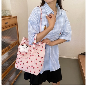 Detail of pink corduroy bucket bag featuring strawberry prints and a plush pendant accessory