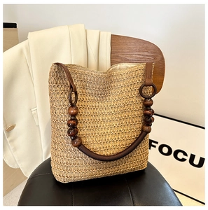 Detail of rainbow straw woven tote bag featuring dark brown wooden bead handle on leather chair