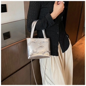 Silver metallic leather handbag with bow accents styled with an elegant outfit