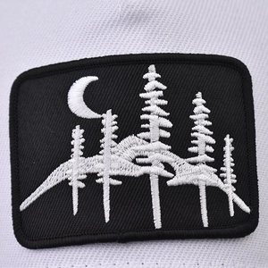 Black rectangular patch featuring white forest and moon embroidery on a mesh baseball cap