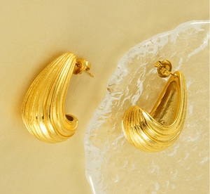Macro detail of gold-plated stainless steel earrings with vertical ribbed texture