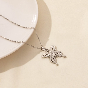 Detail of silver butterfly pendant necklace with intricate hollow design on ceramic plate