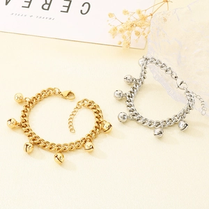 Detail of minimalist 18K gold and silver bell bracelets on a decorative tray