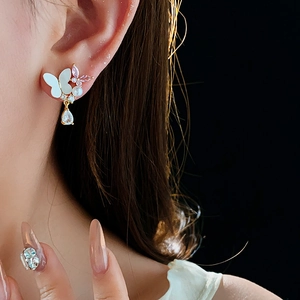 Détail de boucles d'oreilles papillon avec cristaux roses et gouttes sur un mannequin
