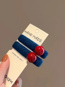 Detail of navy blue velvet hair clip with red bead accents and soft plush texture