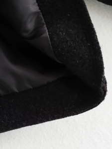Detail of premium black wool coat showing high-quality fabric texture and smooth inner lining