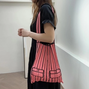Pink knitted tote bag with black stripes shown on a model for a casual shoulder carry