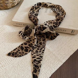 Detailed view of leopard print silk scarf tied on a book with French chic style