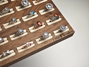 Detailed macro view of assorted gemstone rings on a premium walnut wood jewelry display